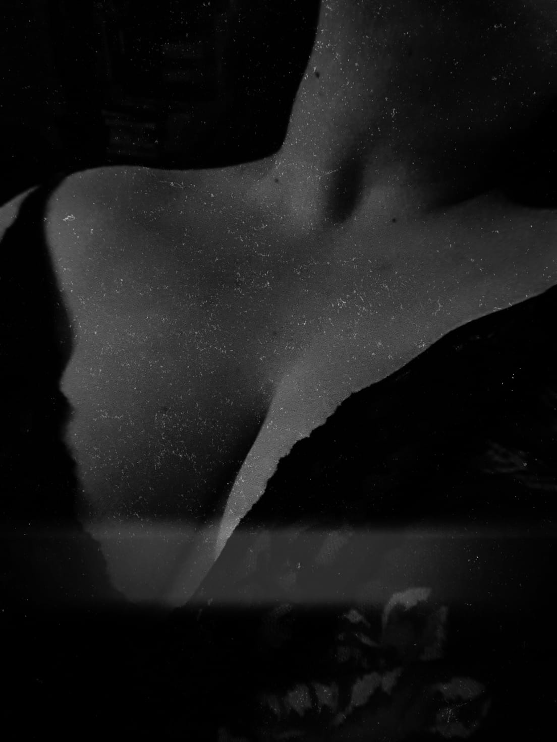 Black and white close-up of a collarbone and shoulder in soft, grainy light