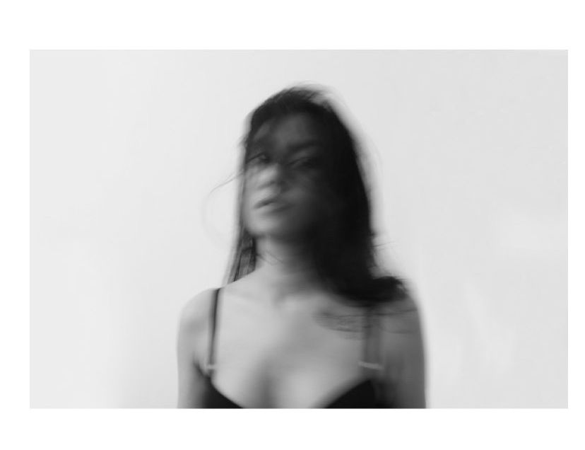 Blurred black and white portrait of a woman with flowing hair against a pale background